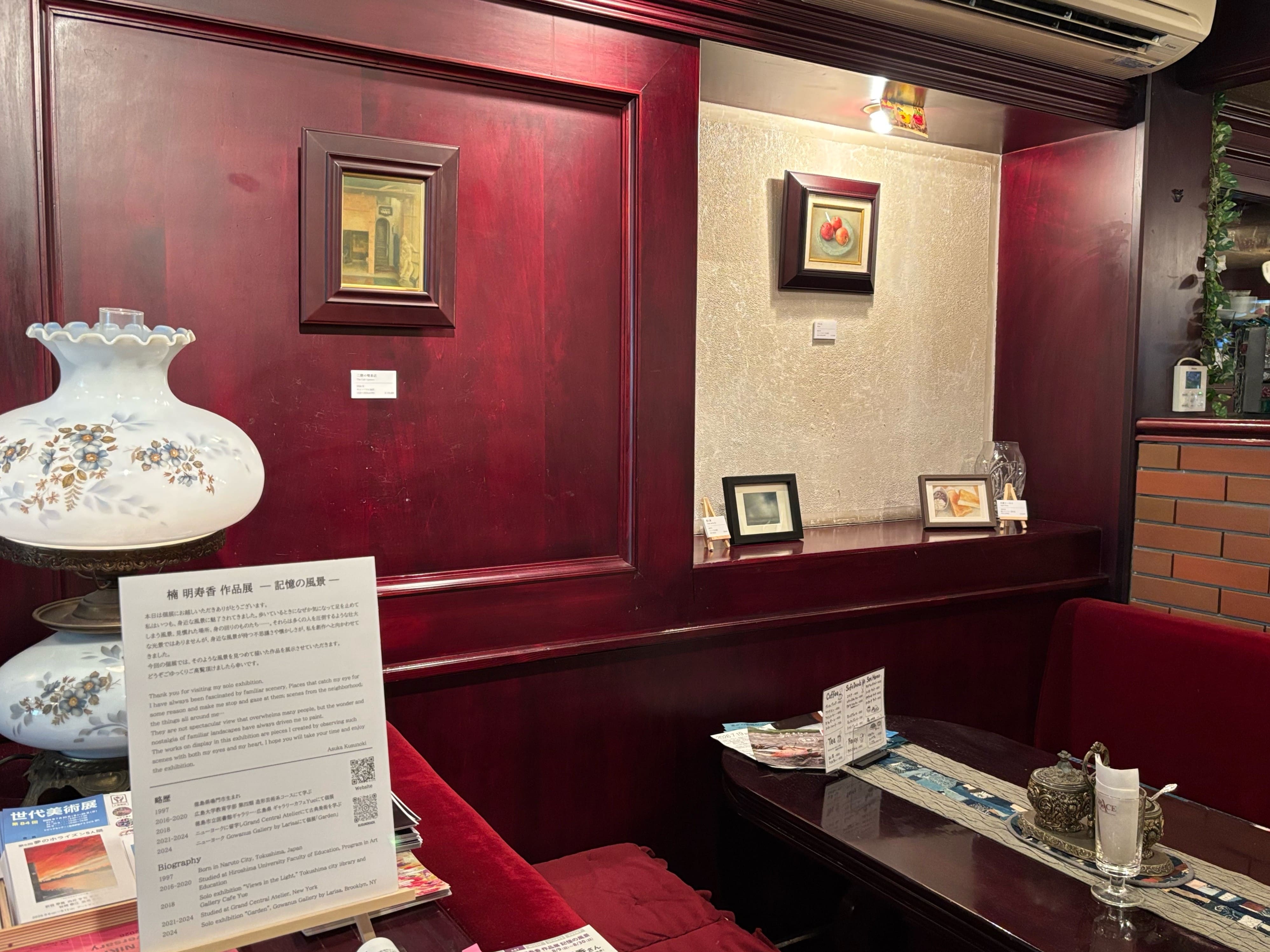 テーブル席の奥の壁や棚に絵が展示されている。