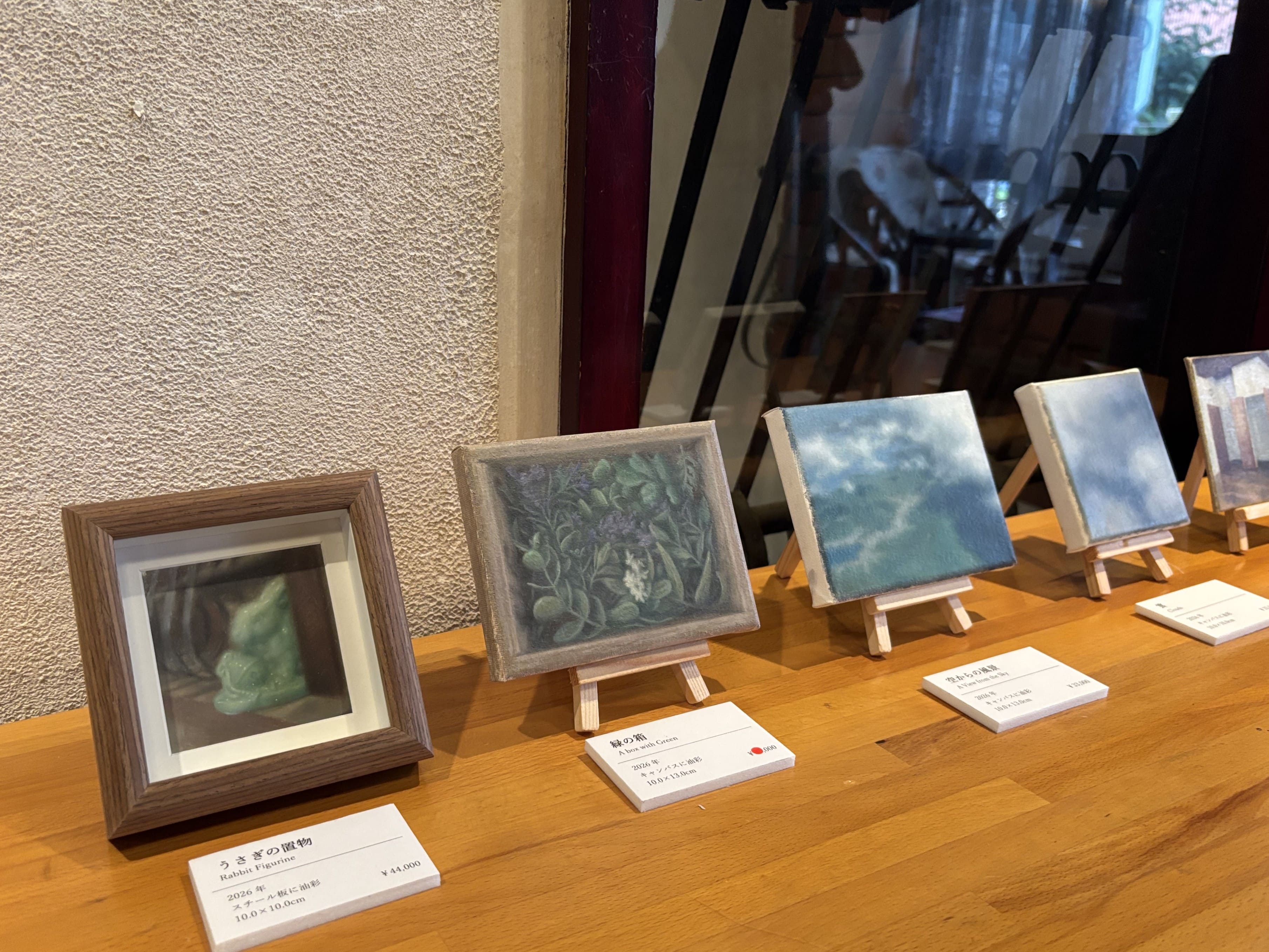ミニイーゼルに置かれた小さい絵画。置物、植物、風景などの絵。