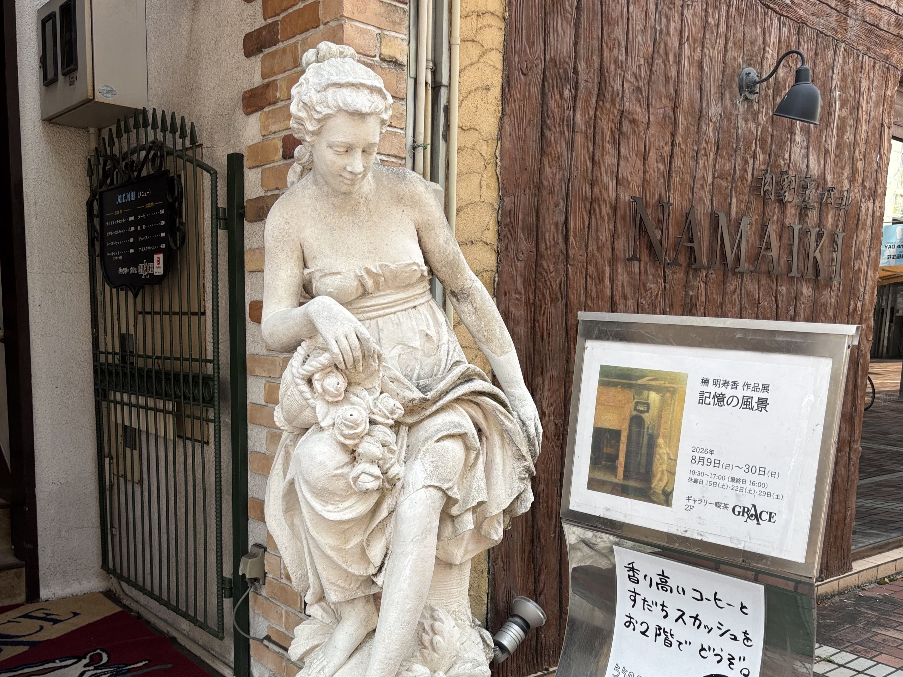 グレイスの入り口に置かれた石の人物彫刻と喫茶店の看板。